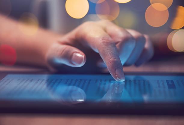 Hands interacting with a tablet computer, showing data or a digital interface